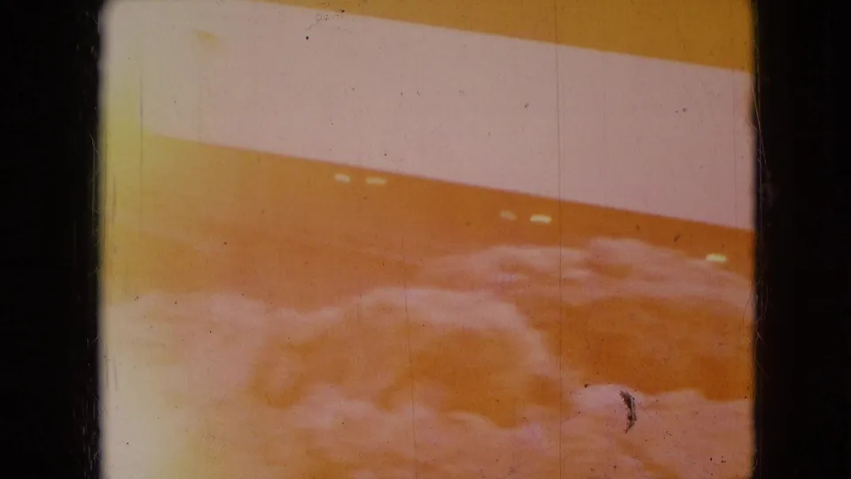 1966 Athens, Ohio 8mm frame with warm color shift, a red-orange and white striped industrial surface, and a pale snowy foreground.