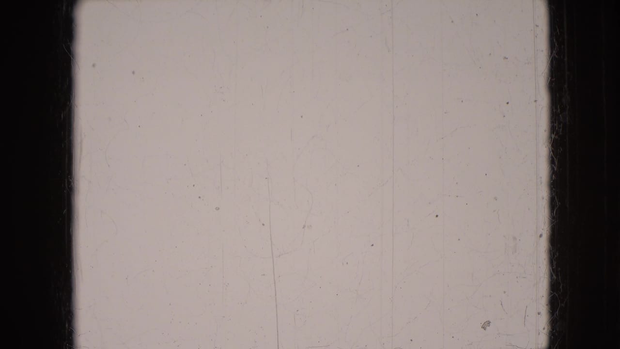 Blank or overexposed 8mm frame from the 1966 Athens, Ohio home-movie clip, with visible scratches, dust, and dark gate edges.