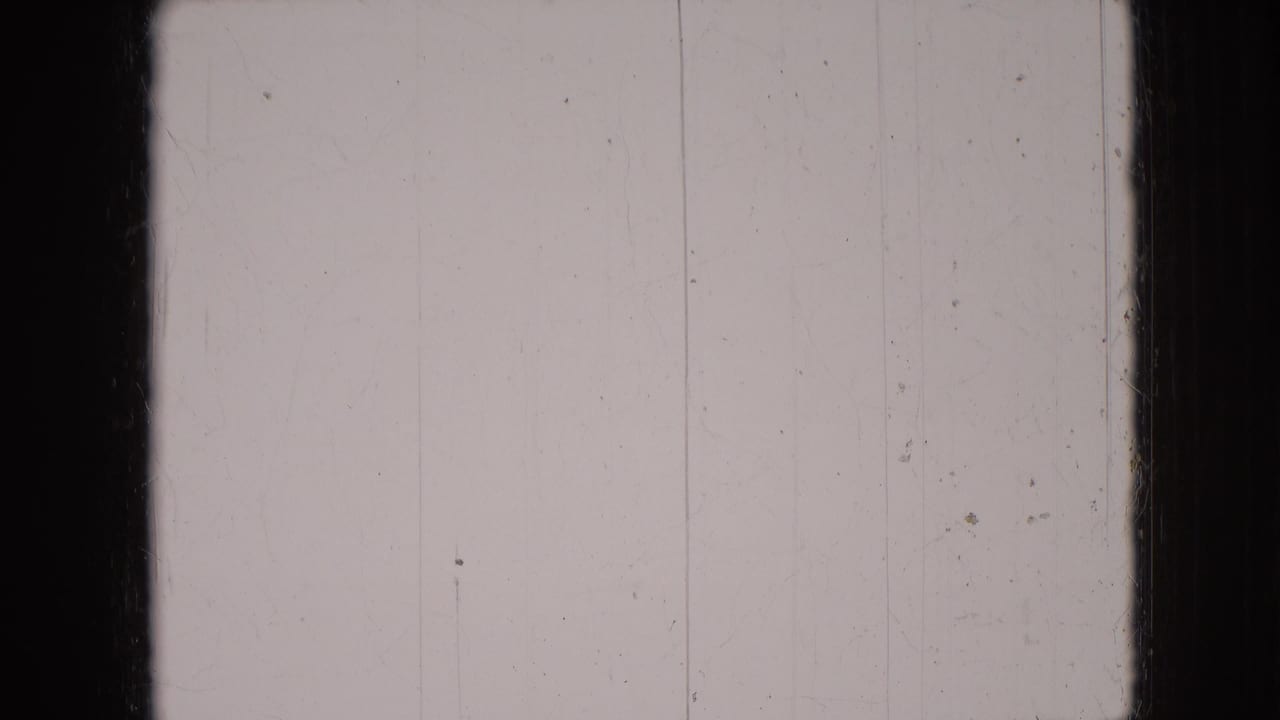 Pale scratched 8mm frame from the metadata-supported 1966 Athens, Ohio clip, showing film wear before the dog scene appears.
