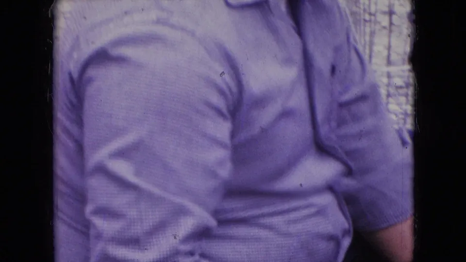 An adult man in a light purple short-sleeve shirt is partly framed beside the car, with only his torso and arms visible in the 1966 Athens, Ohio home-movie shot.