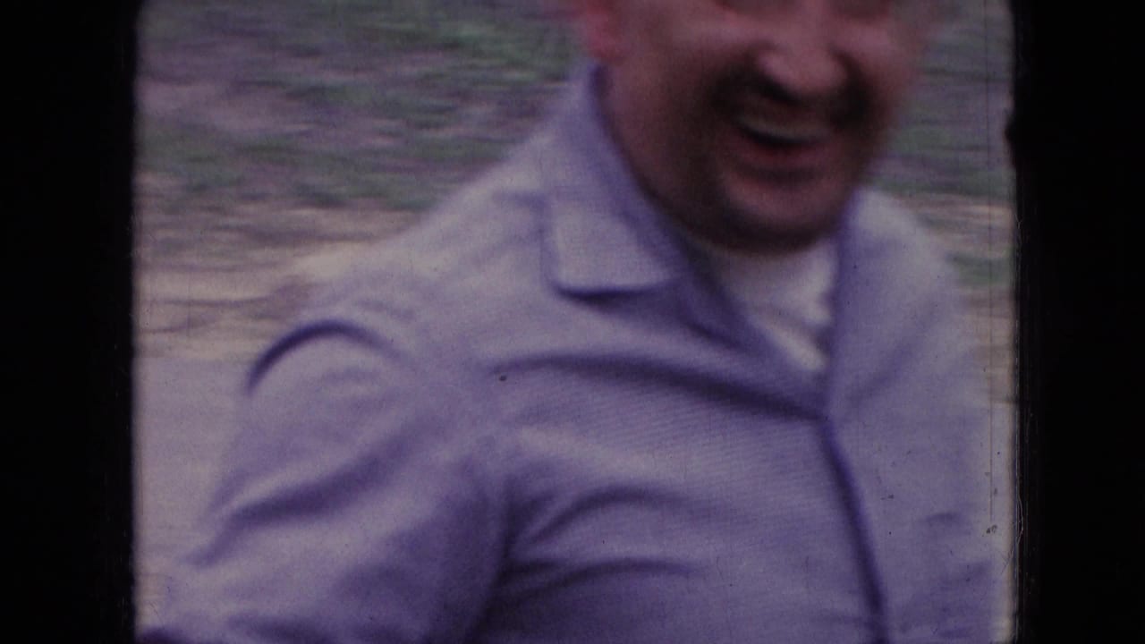 In metadata-supported Athens, Ohio in 1966, a smiling adult man in a light button-up shirt leans close to the handheld 8mm camera outdoors.