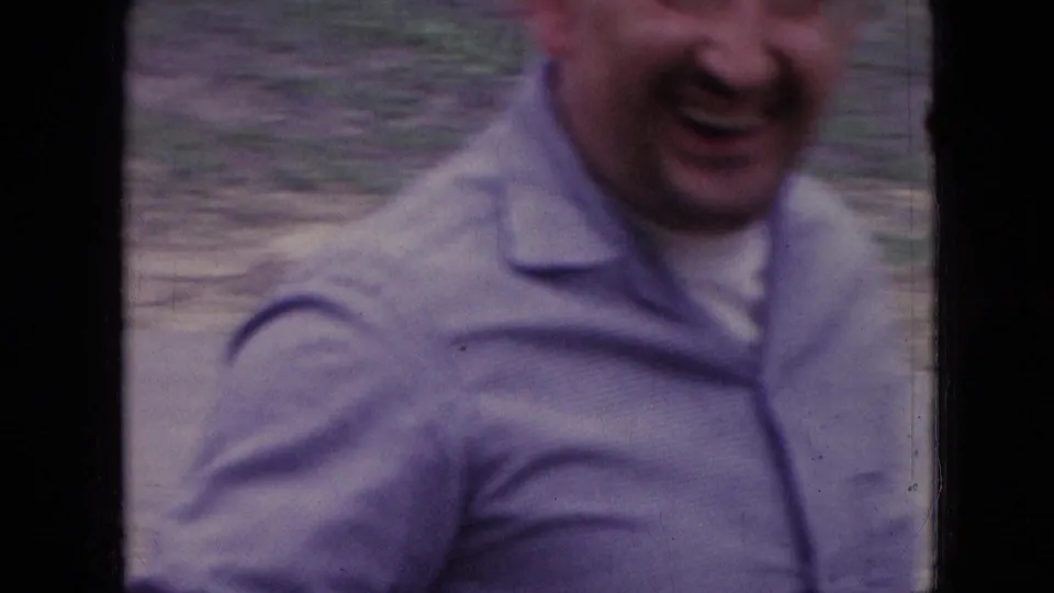 In metadata-supported Athens, Ohio in 1966, a smiling adult man in a light button-up shirt leans close to the handheld 8mm camera outdoors.