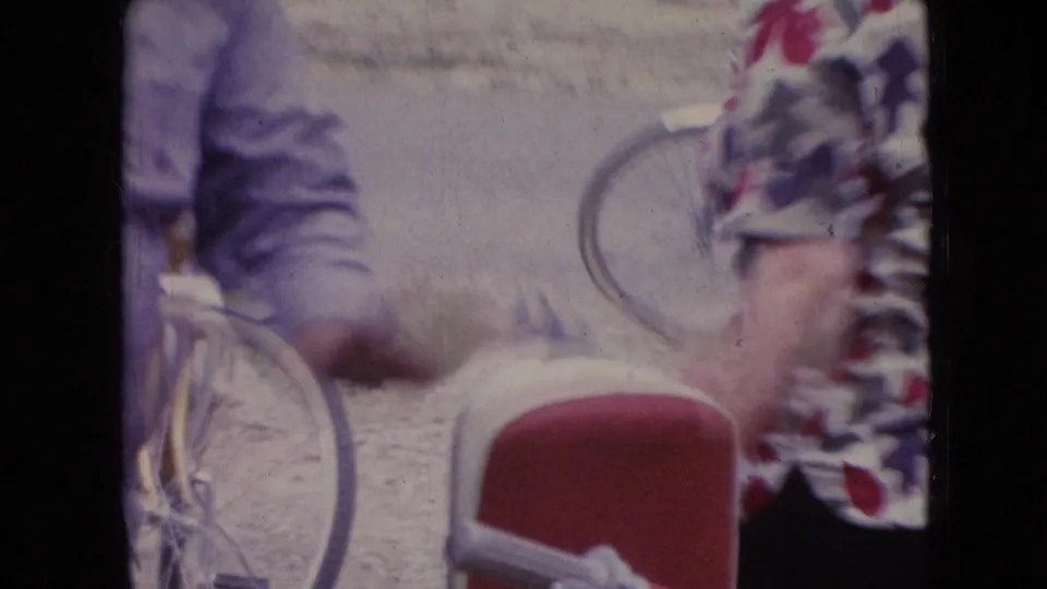 The final frame shows the man near the bicycle, a red chair or seat in the foreground, and a woman in a floral dress at the edge of the 1966 Athens, Ohio home-movie scene.
