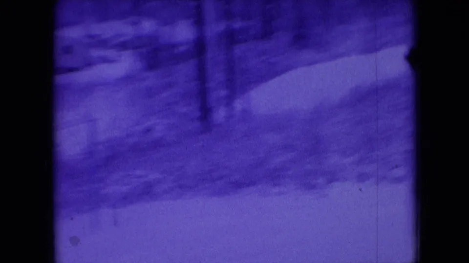 Blue-tinted 1966 8mm home-movie view in Athens, Ohio, showing a snowy yard, bare trees, and a winding path with dark film borders.