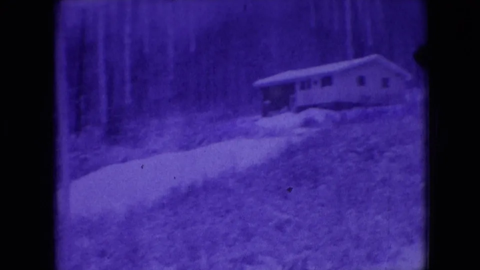 Athens, Ohio 1966 8mm frame showing a small house beyond a snow-covered yard, with bare woods and a winding path in the foreground.