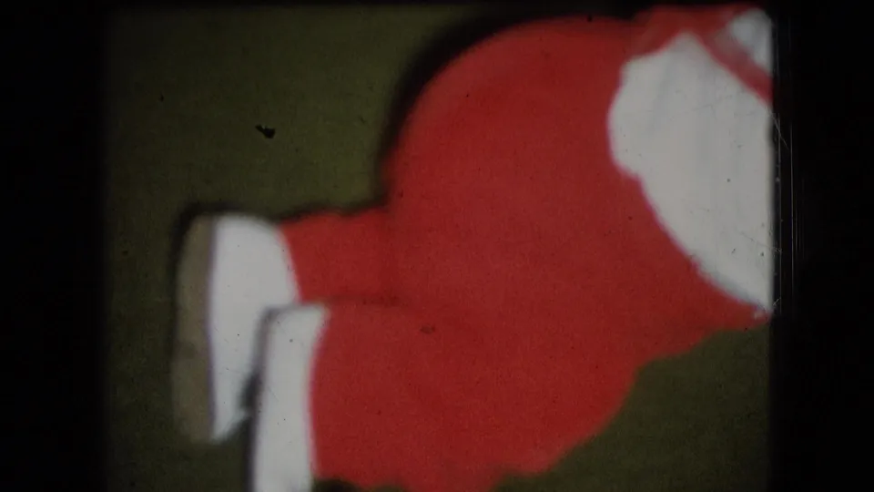 Close 1966 home-movie frame from Athens, Ohio showing the lower half of a small child in red clothing with white shoes on a green carpeted floor.