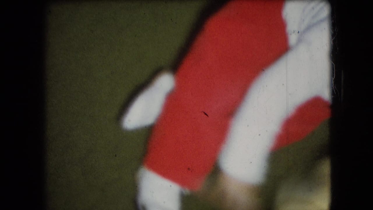 Small child’s legs and torso in red clothing moving across a green floor.