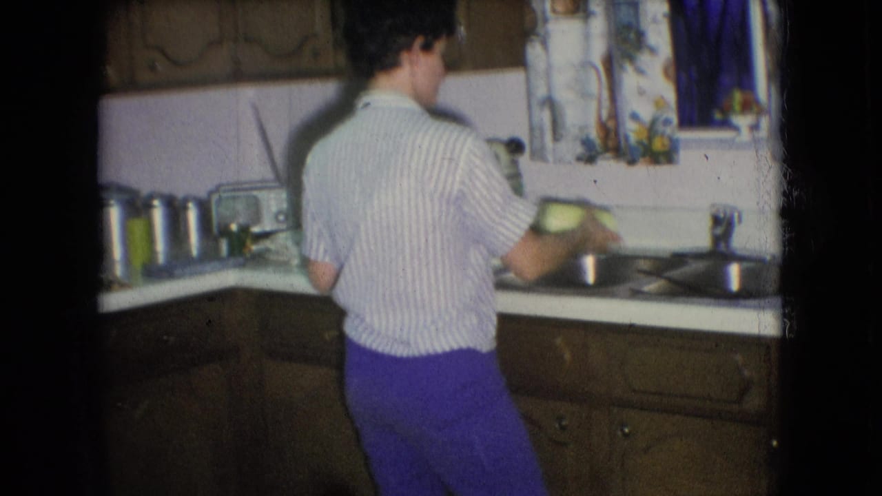 Woman turns slightly while holding an item near the double sink in a kitchen.