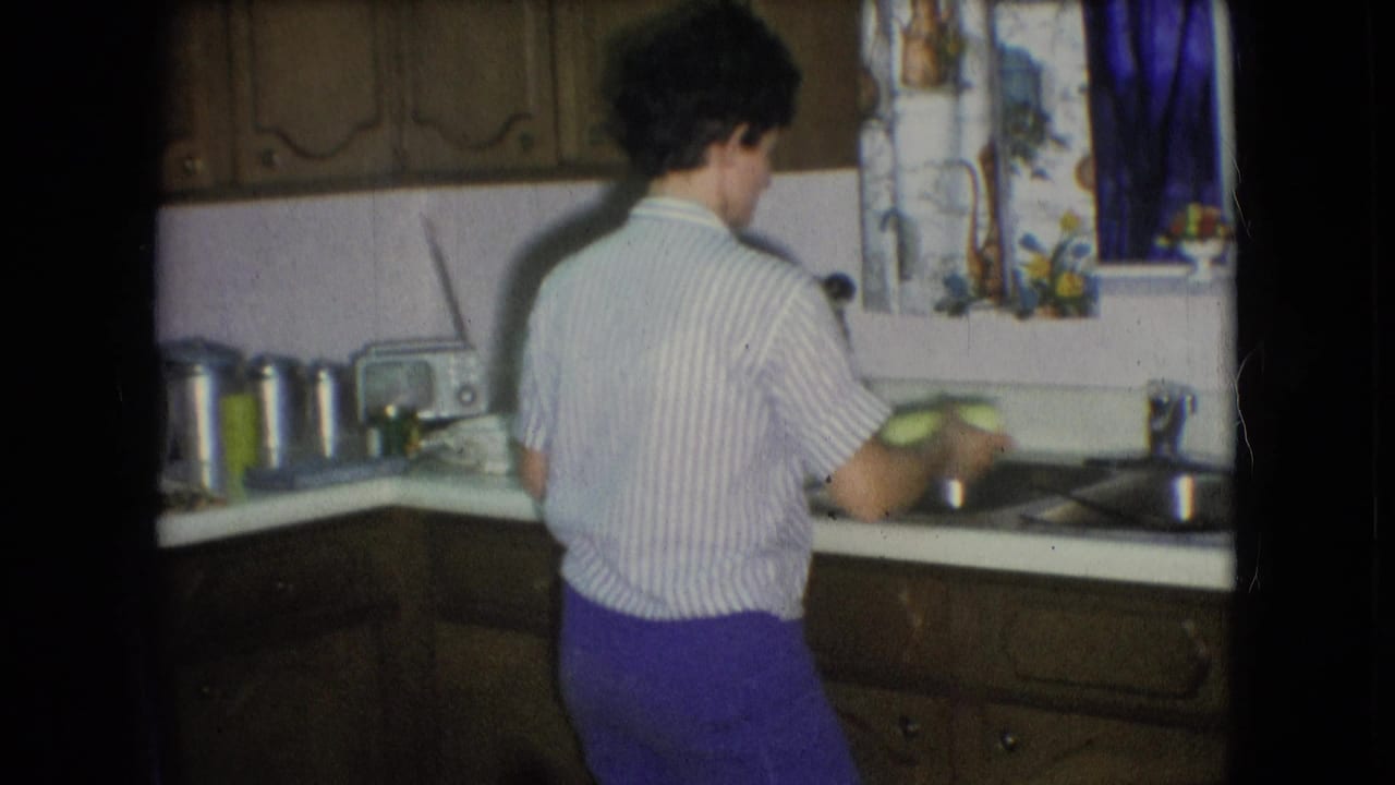 Person turned toward the sink while holding dishes in a kitchen.