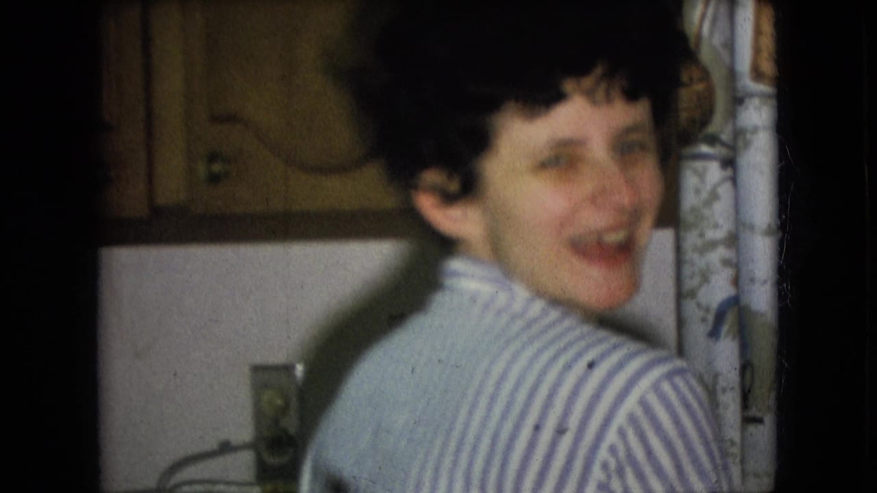Woman turns toward the camera and smiles in a small kitchen.