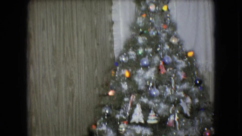Decorated Christmas tree with tinsel, colorful ornaments, and small lights inside a wood-paneled Athens, Ohio home documented as 1966 8mm footage.