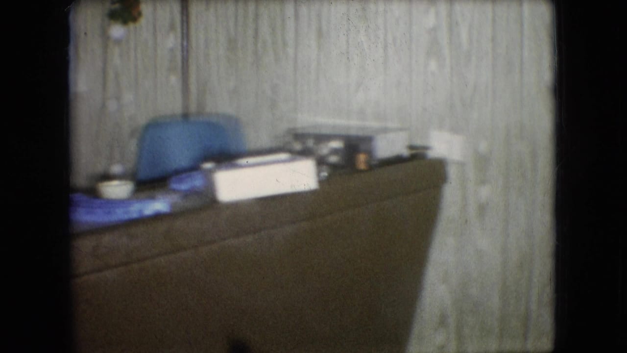 Desk or counter area with a blue chair, papers, containers, and household items in a 1966 Athens, Ohio domestic interior.