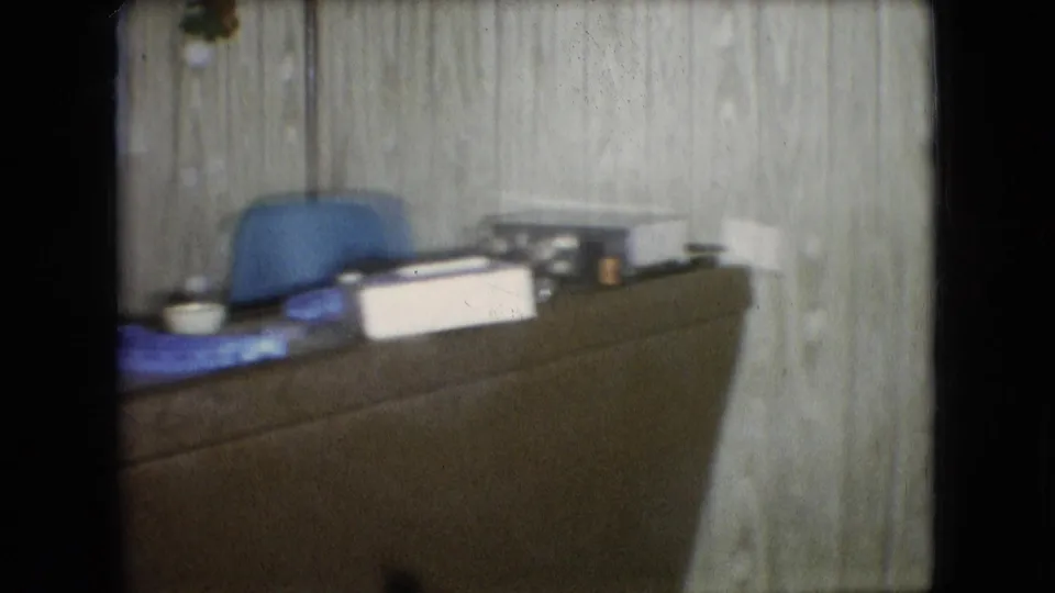 Desk or counter area with a blue chair, papers, containers, and household items in a 1966 Athens, Ohio domestic interior.