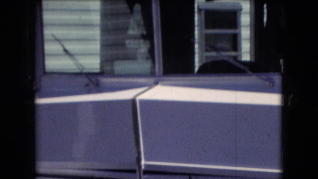 Athens, Ohio 1966 home-movie frame showing the front area of a white recreational vehicle with dark grille vents, window glass, and blue-toned trim.