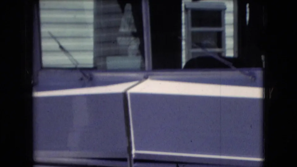 Athens, Ohio 1966 home-movie frame showing the front area of a white recreational vehicle with dark grille vents, window glass, and blue-toned trim.