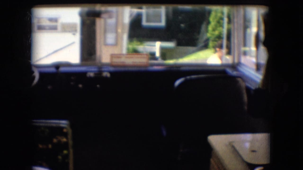 Camper dashboard and front windows with dark seats and a suburban exterior beyond the glass.