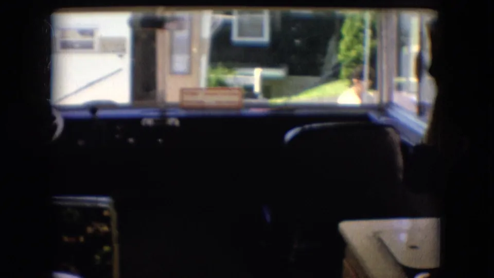 1966 Athens, Ohio 8mm frame looking across a camper dashboard and front seating toward bright windows with a suburban yard and a possible person outside.