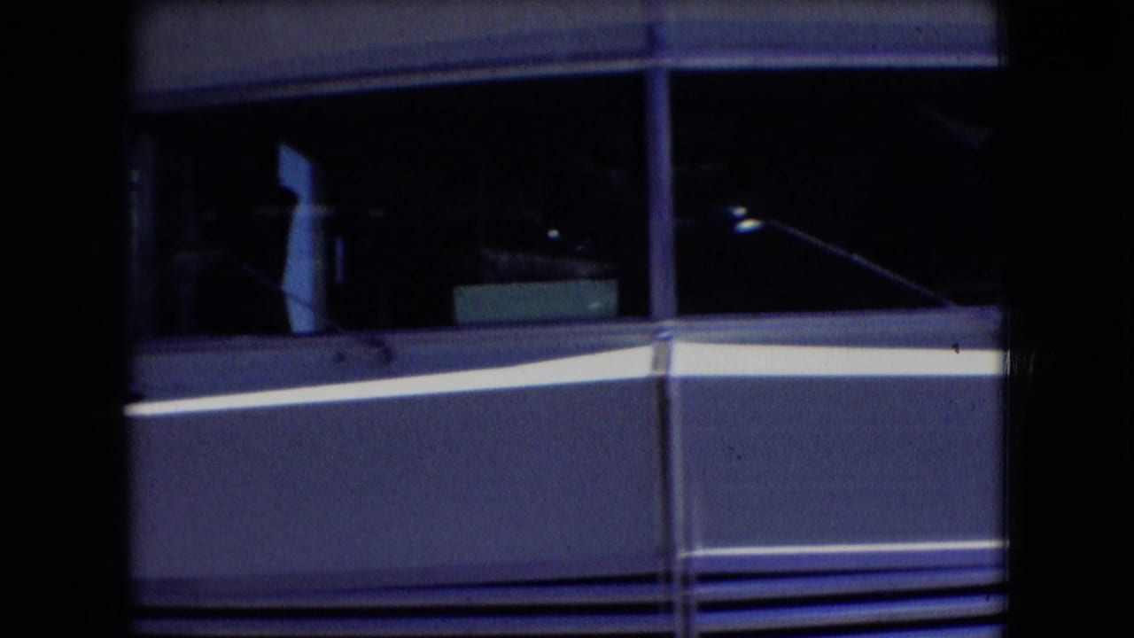 Dark 8mm frame showing the side window and silver body panel of a motorhome, supported by the supplied 1966 Athens, Ohio clip metadata.