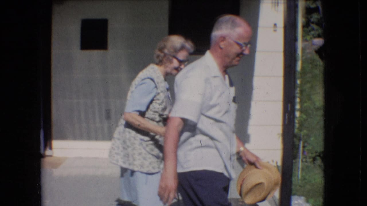 Older couple walks from a porch, with the man holding a straw hat.
