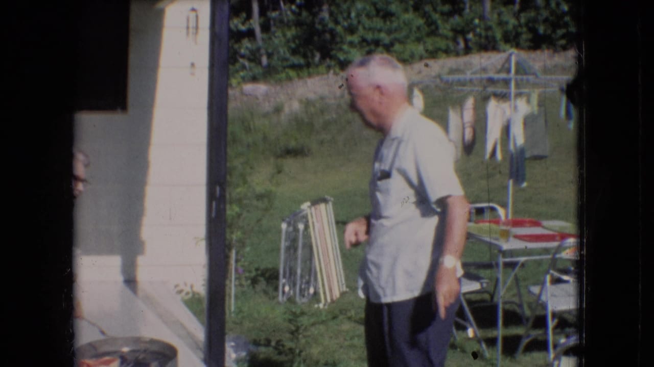 In a 1966 Athens, Ohio backyard scene, an older man in a light shirt stands near porch steps while lawn chairs and a clothesline are visible in the yard.