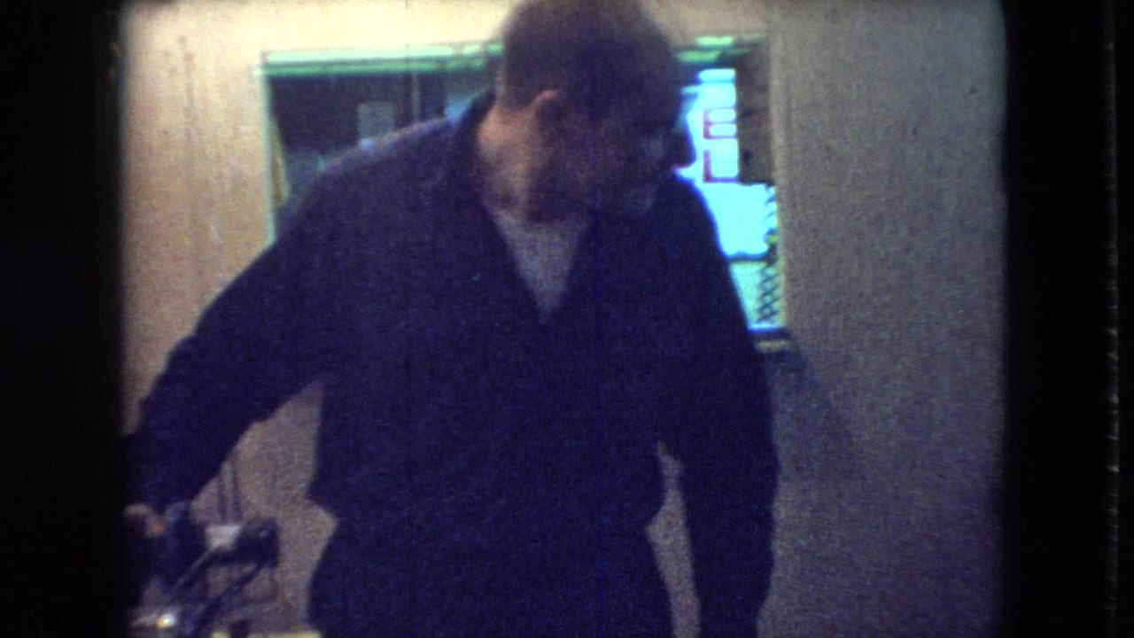 Man leaning near a television in a wood-paneled room.