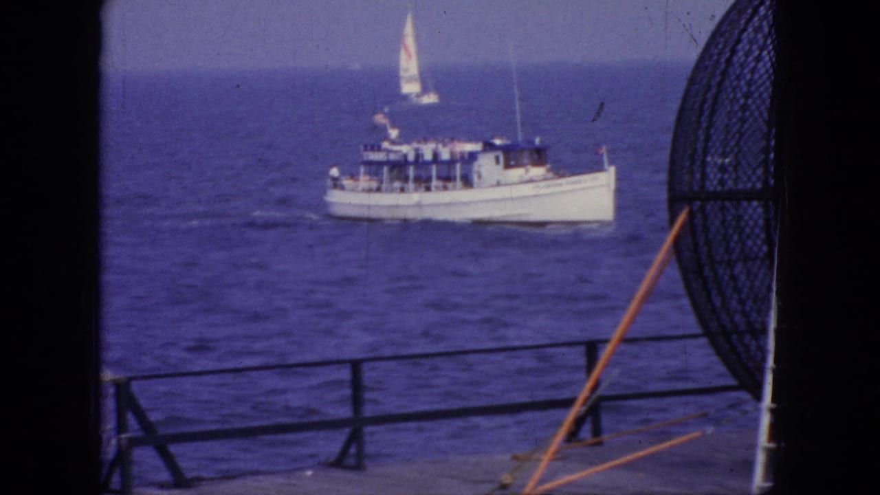 1966 New Jersey coastal footage showing a white motorboat on open water, framed by pier railings and a large circular net or rigging shape in the foreground.
