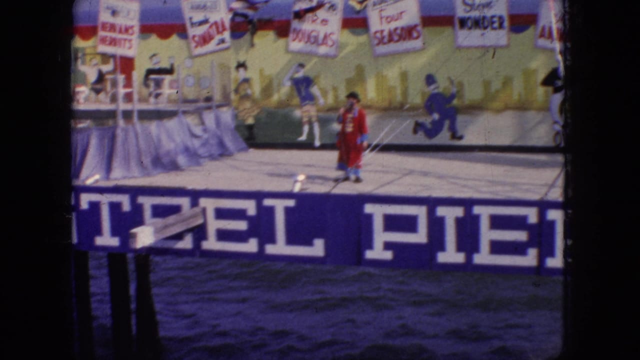 A pier stage show scene in 1966 New Jersey shows a red-costumed performer in front of painted signage and backdrop names, with distant figures on the stage area.