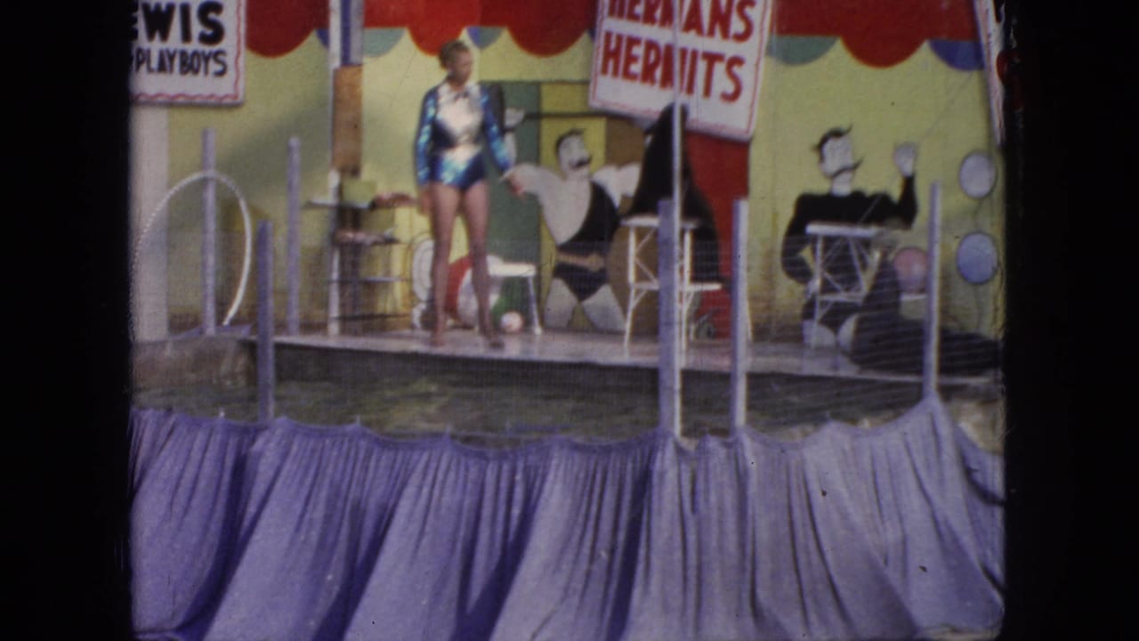 The 1966 Steel Pier show stage shows a woman performer near the pool, painted entertainer cutouts, railings, and readable music-act signs in the background.