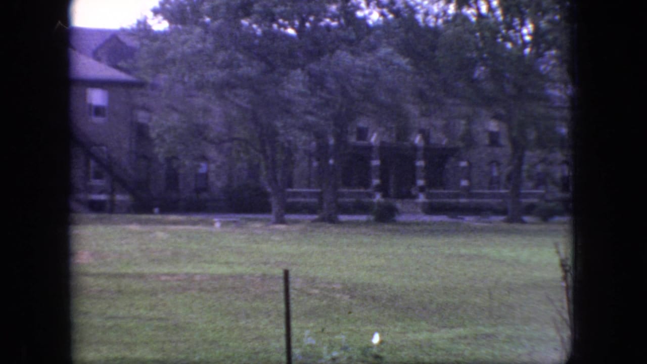 Brick building and trees across an open grassy area.
