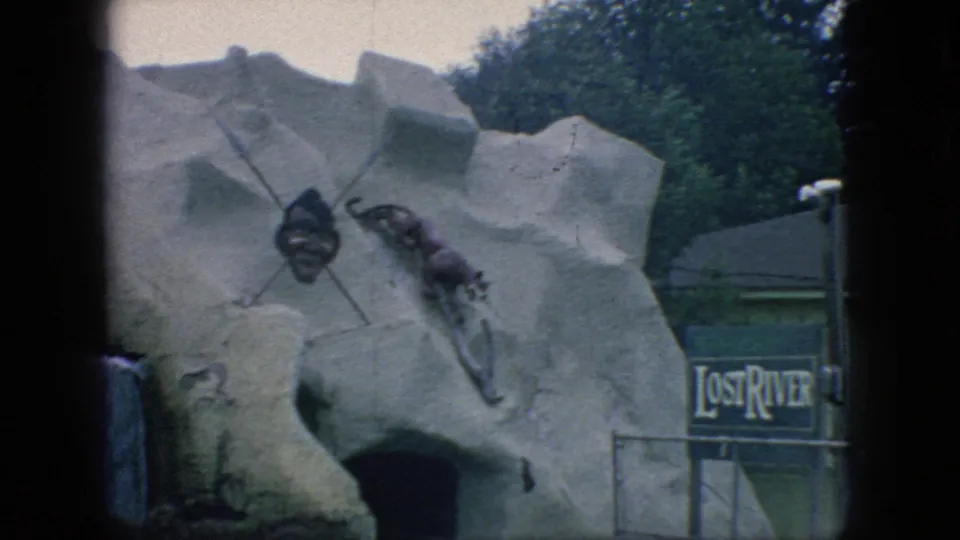1966 New Jersey 8mm frame showing the Lost River amusement ride facade with a simulated rock cave entrance, mounted props, and partial signage.