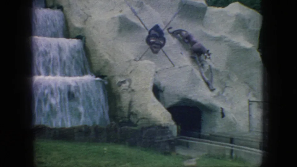 1966 New Jersey 8mm frame showing a cascading waterfall next to the Lost River ride's simulated rock facade and dark cave opening.