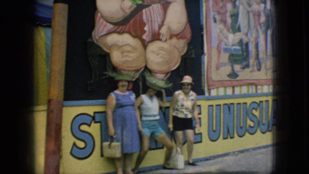 Three women in 1960s summer attire stand in front of colorful carnival art and partial lettering in supplied 1966 New Jersey footage.