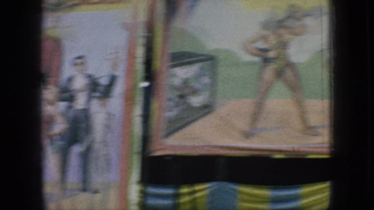 A handheld 8mm frame shows painted carnival display panels with illustrated figures and muted color, likely part of the same New Jersey amusement setting.