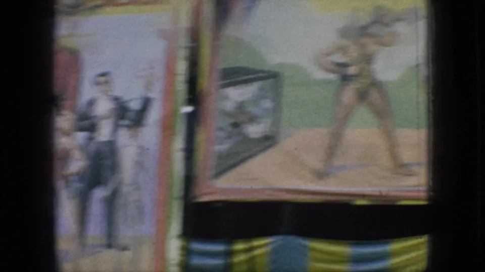 A handheld 8mm frame shows painted carnival display panels with illustrated figures and muted color, likely part of the same New Jersey amusement setting.