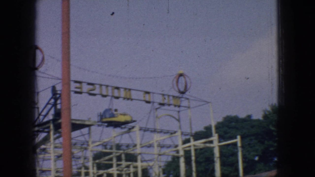 Small roller coaster structure with a ride car and overhead sign framework.