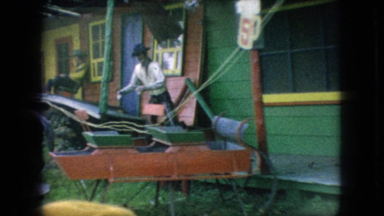 Cowboy-hatted figure near a small ride or carriage beside colorful wooden facades.
