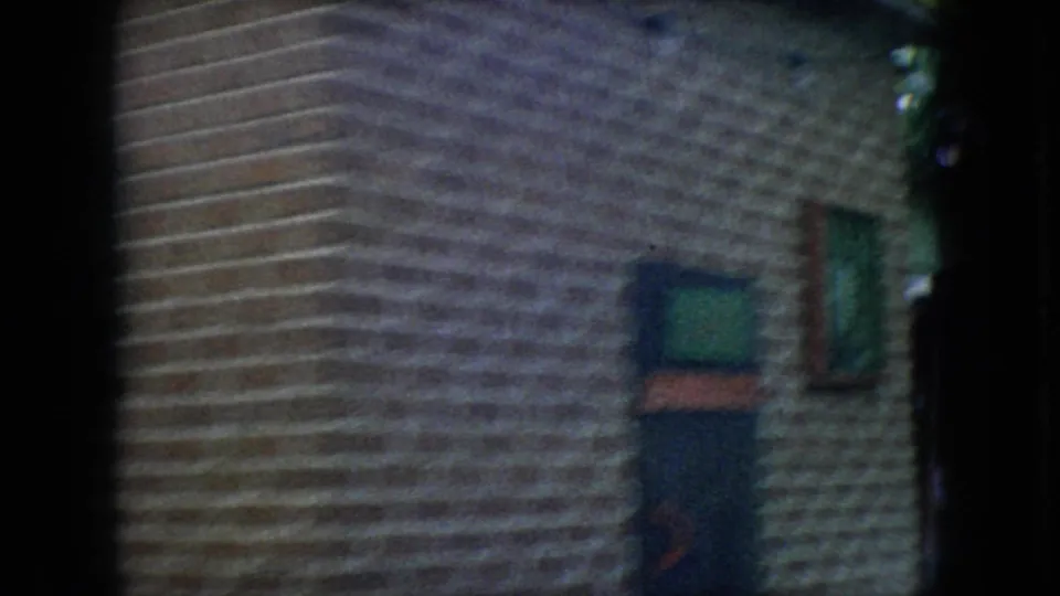 The final frame shows a brick building exterior with windows and a partial glimpse of the passing mule team at the edge of the 8mm frame.