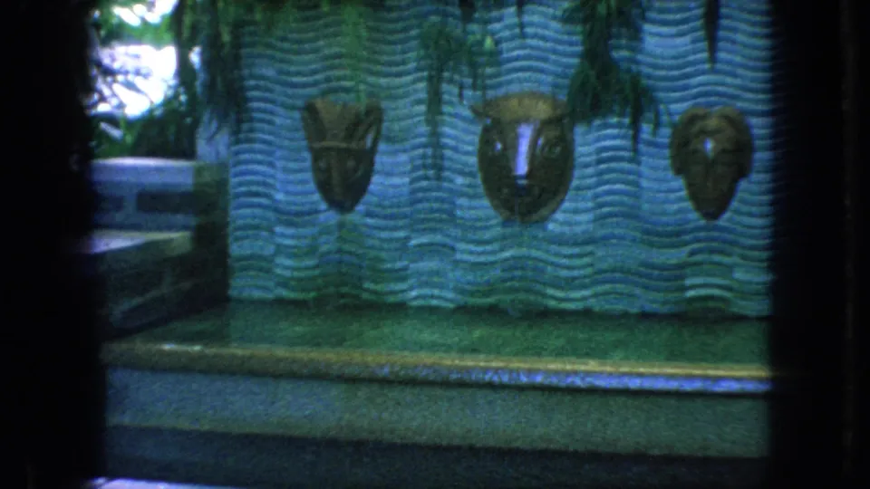 Decorative zoo wall in the 1966 New Jersey footage, showing three carved animal masks mounted on a wavy blue surface beside a walkway.