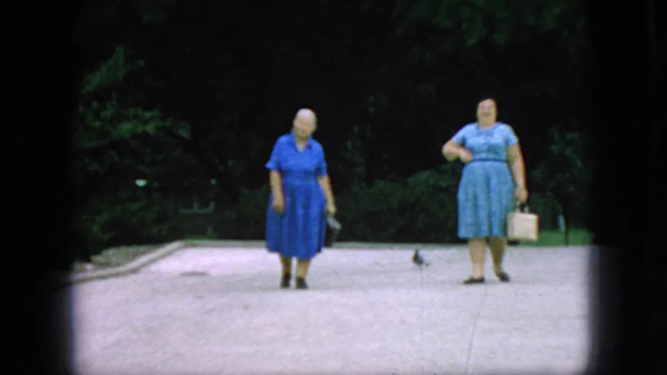 Two older women in blue dresses appear on a paved park path in New Jersey, filmed from a distance in 1966 home-movie footage.