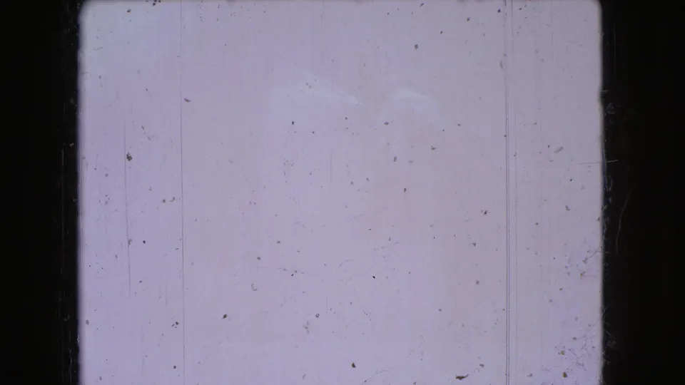 A mostly blank 8mm frame from the 1966 Ohio home-movie clip, showing pale exposure, dust specks, vertical scratches, and dark rounded frame edges.