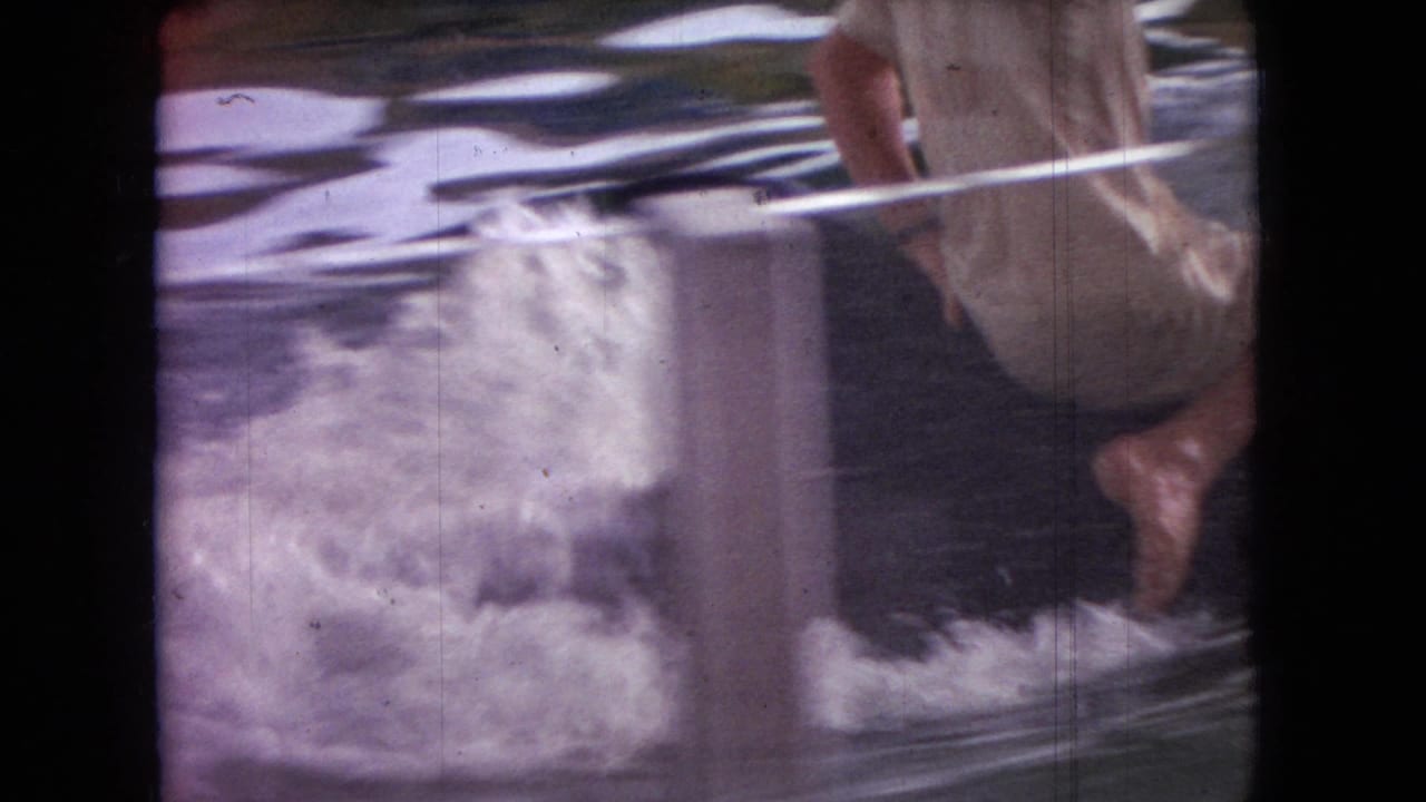 Partial rider above splashing water beside a vertical tank post.