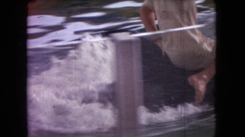A partially visible man rides near the edge of a mechanical whale water attraction in the 1966 Ohio home-movie footage, with foam and spray around the tank post.