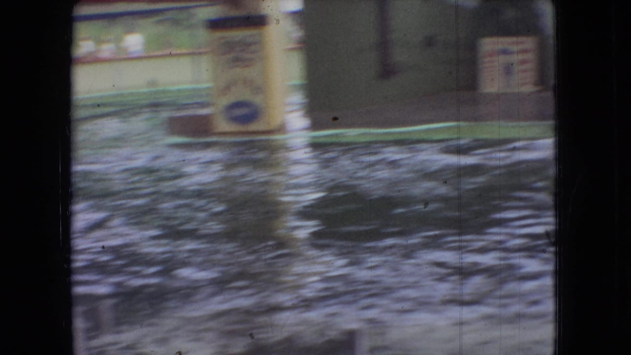 Soft, motion-blurred 1966 Ohio 8mm frame looking across a water-filled arena toward indistinct show structures.