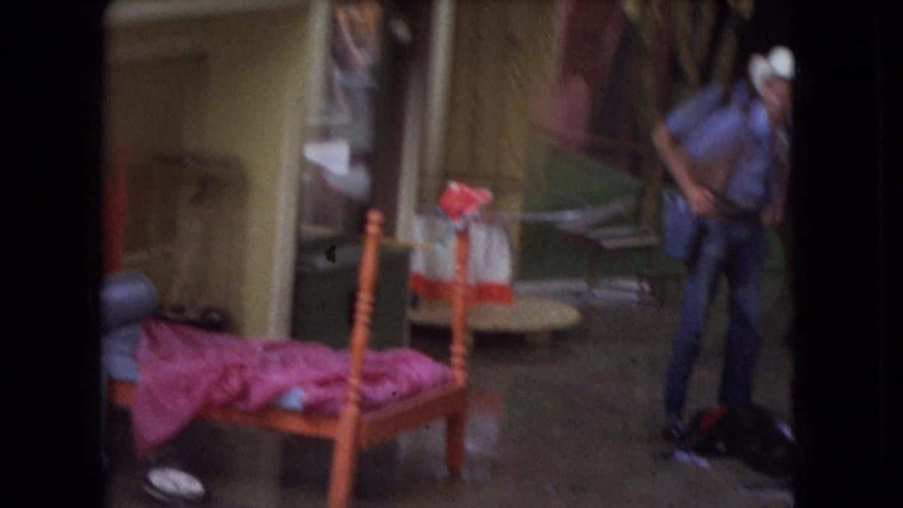 Trainer in a cowboy hat stands near a themed set with a small bed and pink bedding.