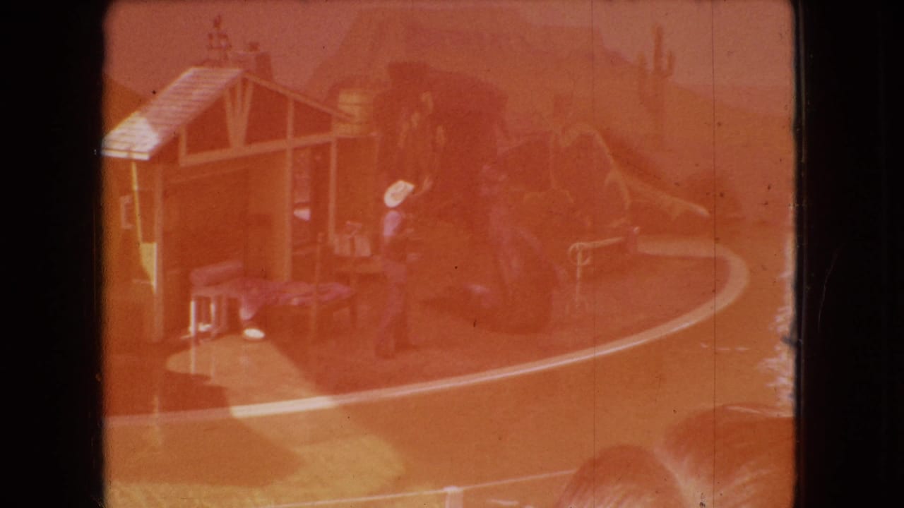Faded orange frame of the same sea lion performance set and trainer.