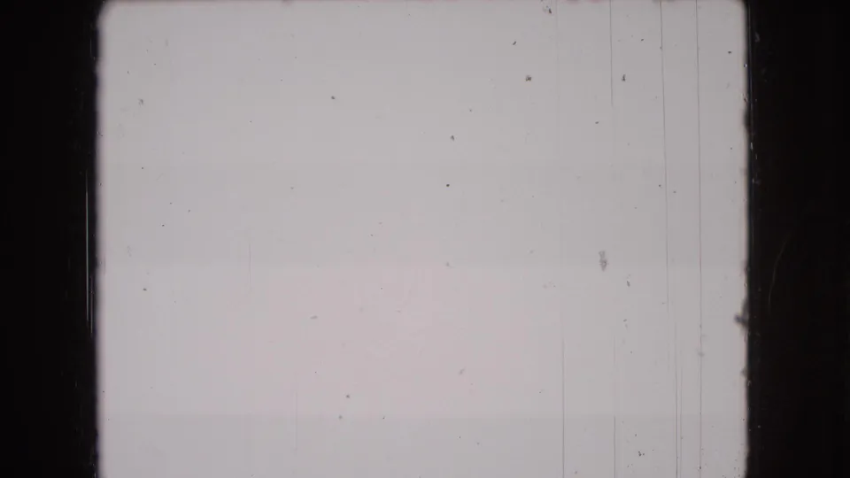 End frame from the scanned 8mm clip, largely blank with pale gray exposure, vertical scratch lines, dust, and dark film borders.