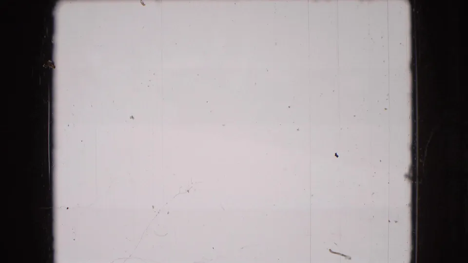 Mostly blank or overexposed 8mm frame with dark film borders, small dust specks, vertical scratches, and no clear subject visible.