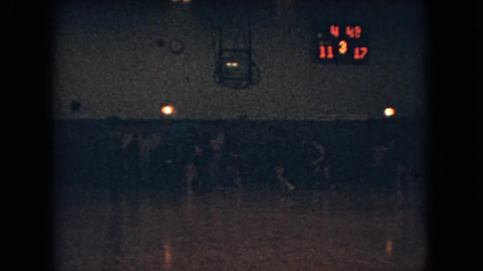 Dim 1966 Ohio school basketball game frame with players moving across a gym floor under a scoreboard showing 11-17 and 4:48 remaining.