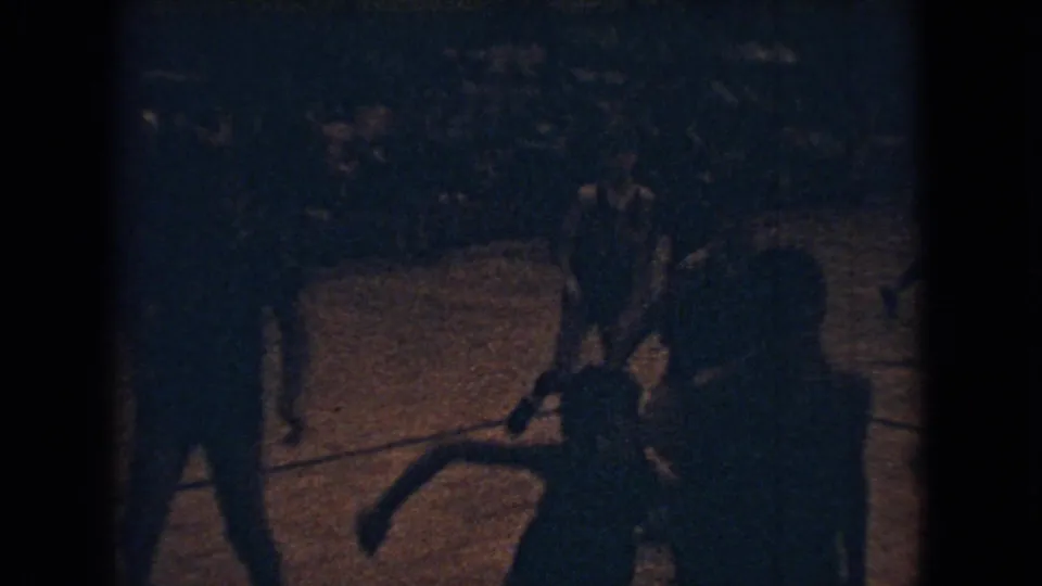 A clearer 8mm frame shows nighttime basketball action on a lit court area, with shadowed figures nearby and one player or participant bending forward in the foreground.