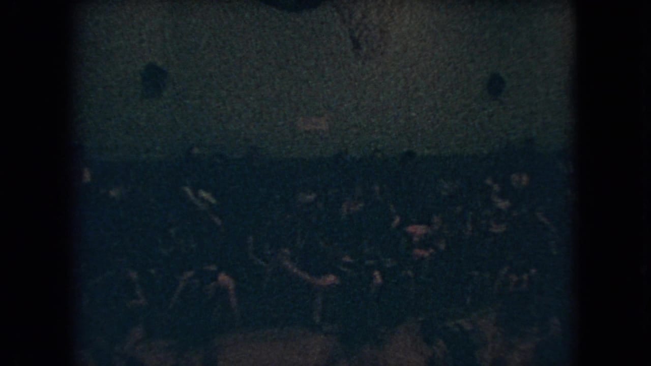Players cluster near the far side of the court while spectators watch from behind them.